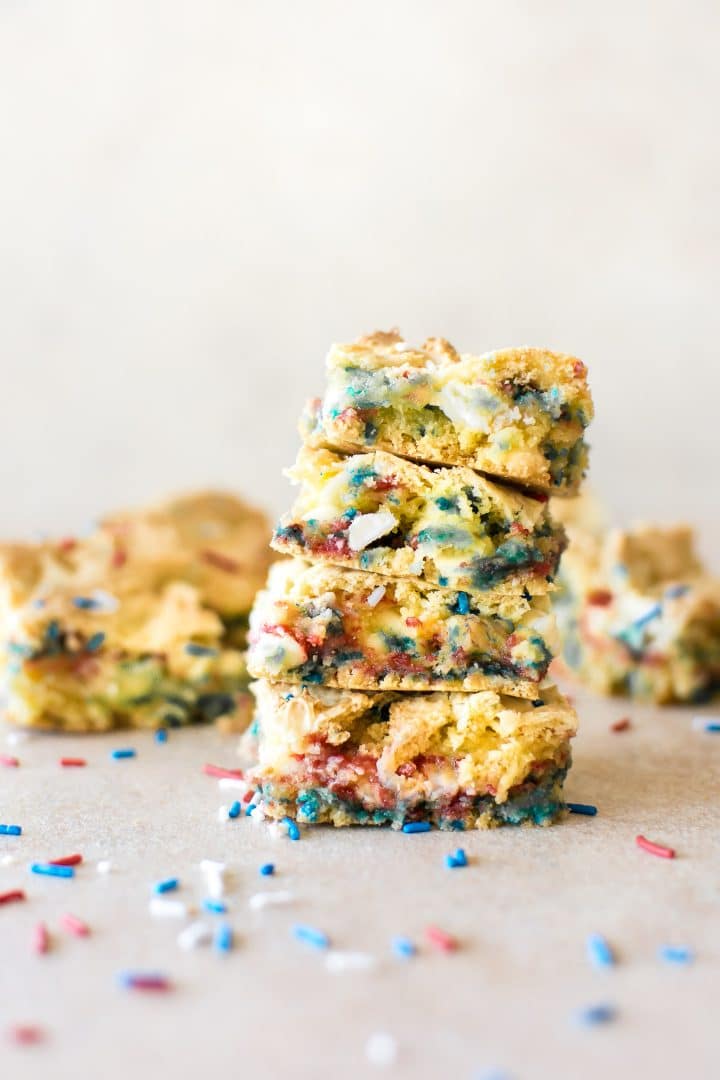 a stack of four patriotic fourth of july cookie bars with sprinkles