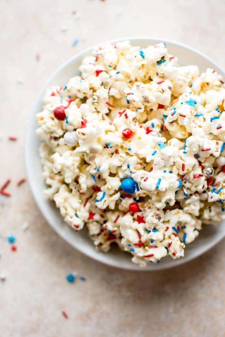 popcorn drizzled with marshmallows and red, white, and blue sprinkles in a bowl