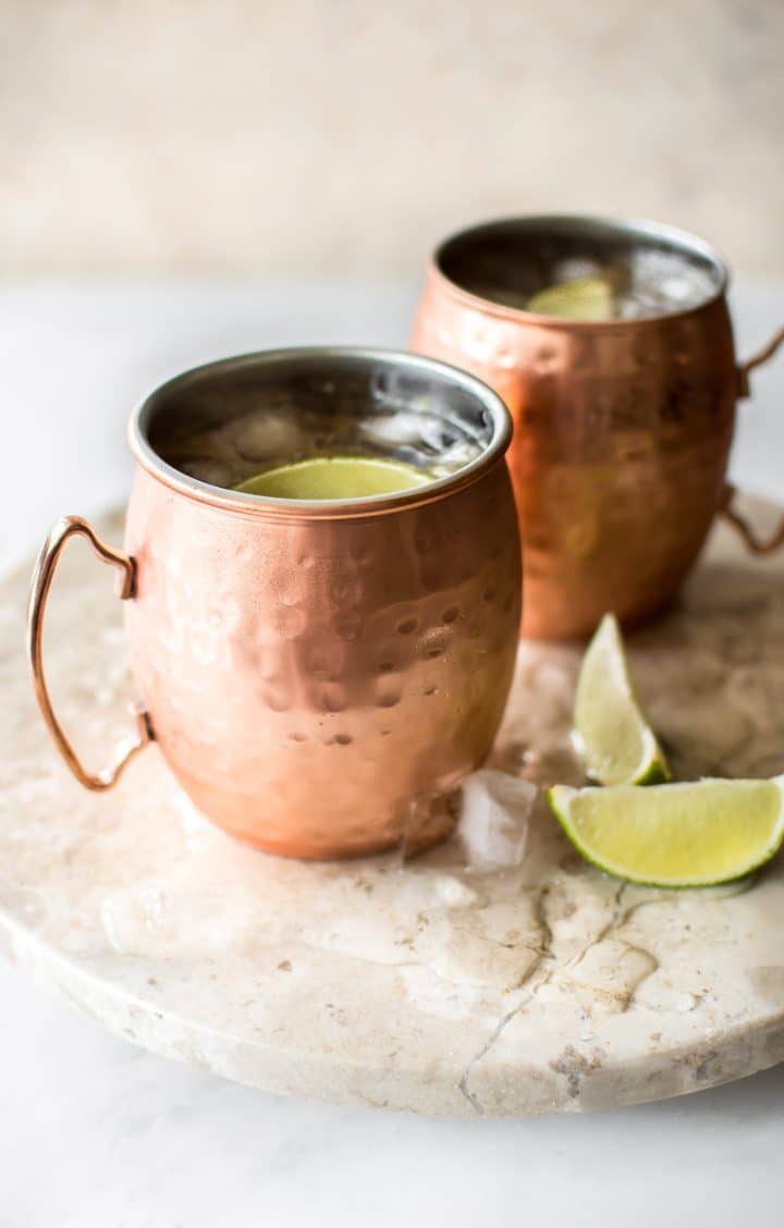 two rhubarb Moscow mules in copper mugs with lime wedges