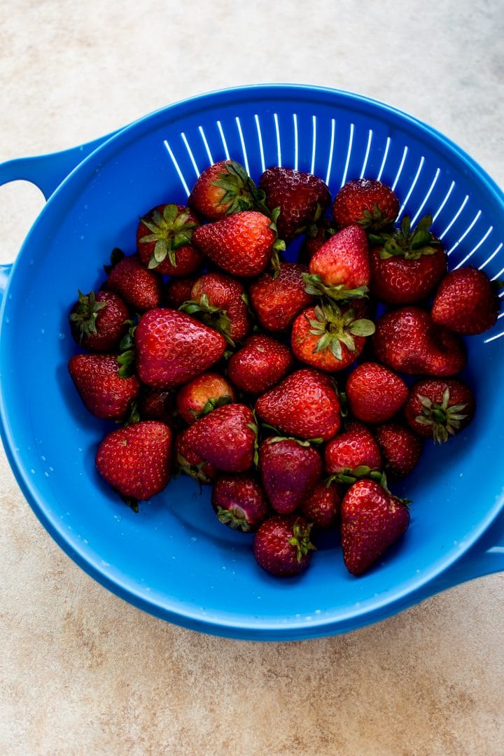 a large colander with fresh whole strawberries