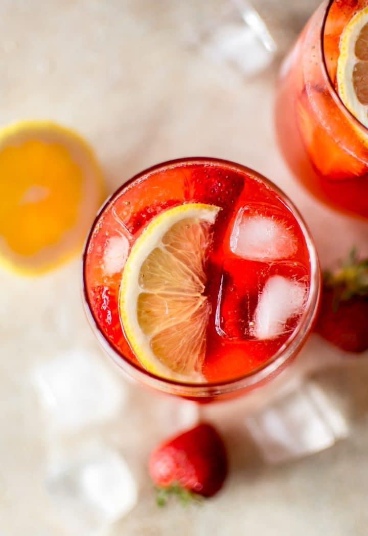 close-up of a glass of strawberry lemonade with ice and slice of lemon