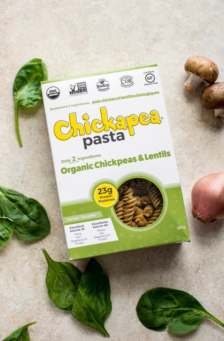 a box of Chickapea pasta beside raw mushrooms and basil leaves