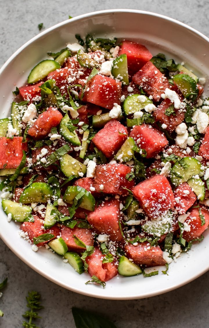 close-up of watermelon, basil, cucumber, and feta salad in a white bowl