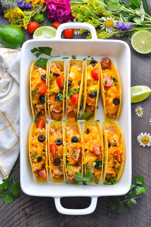 several baked chicken tacos in a white casserole dish
