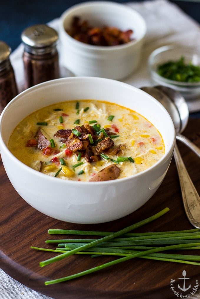 creamy chicken corn chowder with bacon in a white bowl on a wooden board