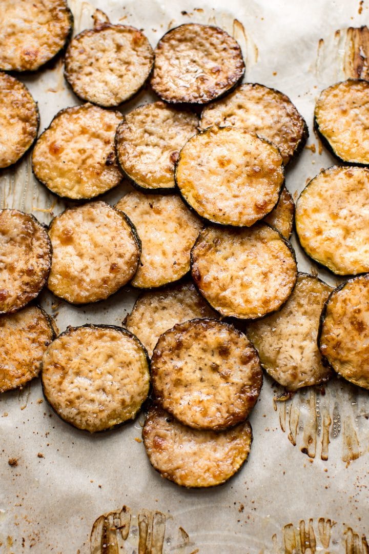 several baked parmesan zucchini rounds on parchment paper