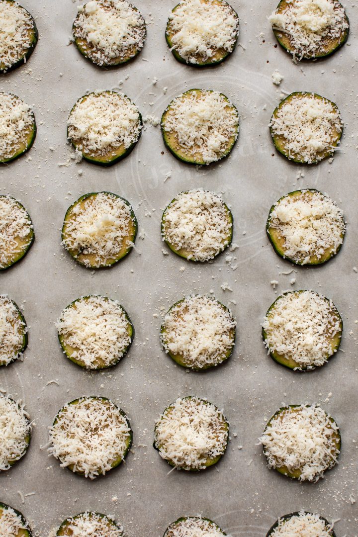 parmesan zucchini rounds on a baking tray ready for the oven