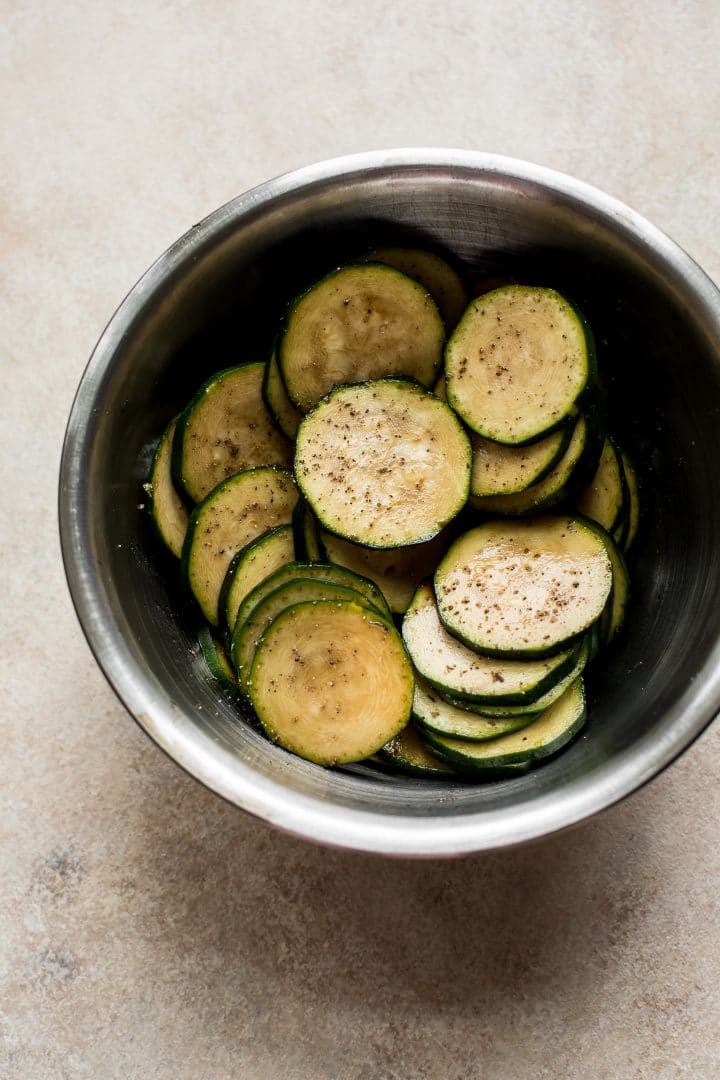 raw sliced zucchini rounds in a metal prep bowl