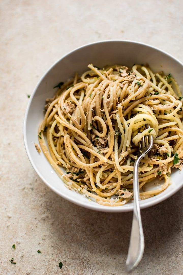 healthy 15 minute garlic tuna pasta in a bowl with spaghetti twirled on a fork