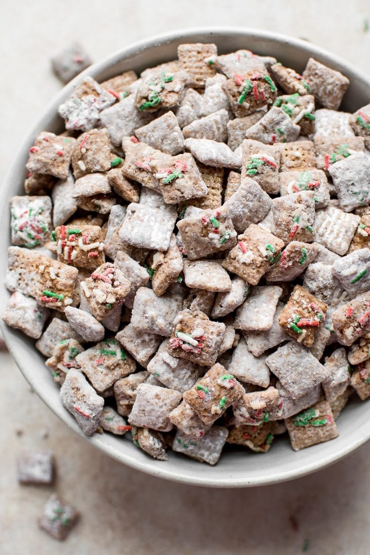 close-up of Christmas puppy chow mix with powdered sugar, gluten-free rice Chex cereal, and plenty of sprinkles in a bowl