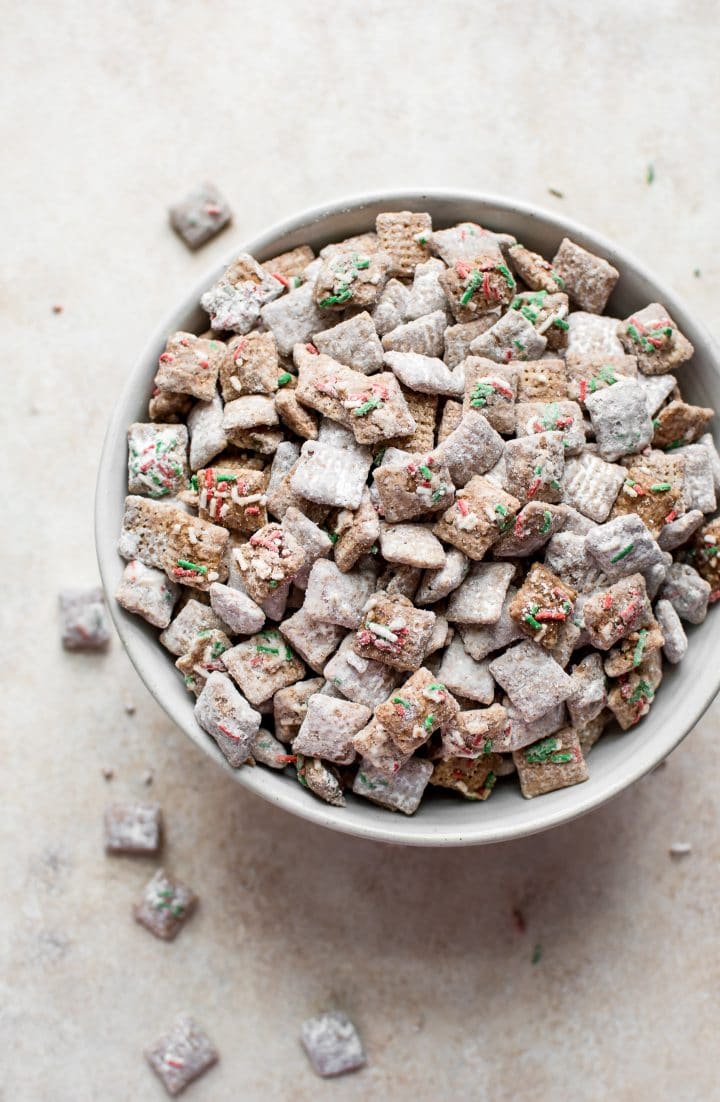 white bowl with Christmas muddy buddies with festive red and green sprinkles