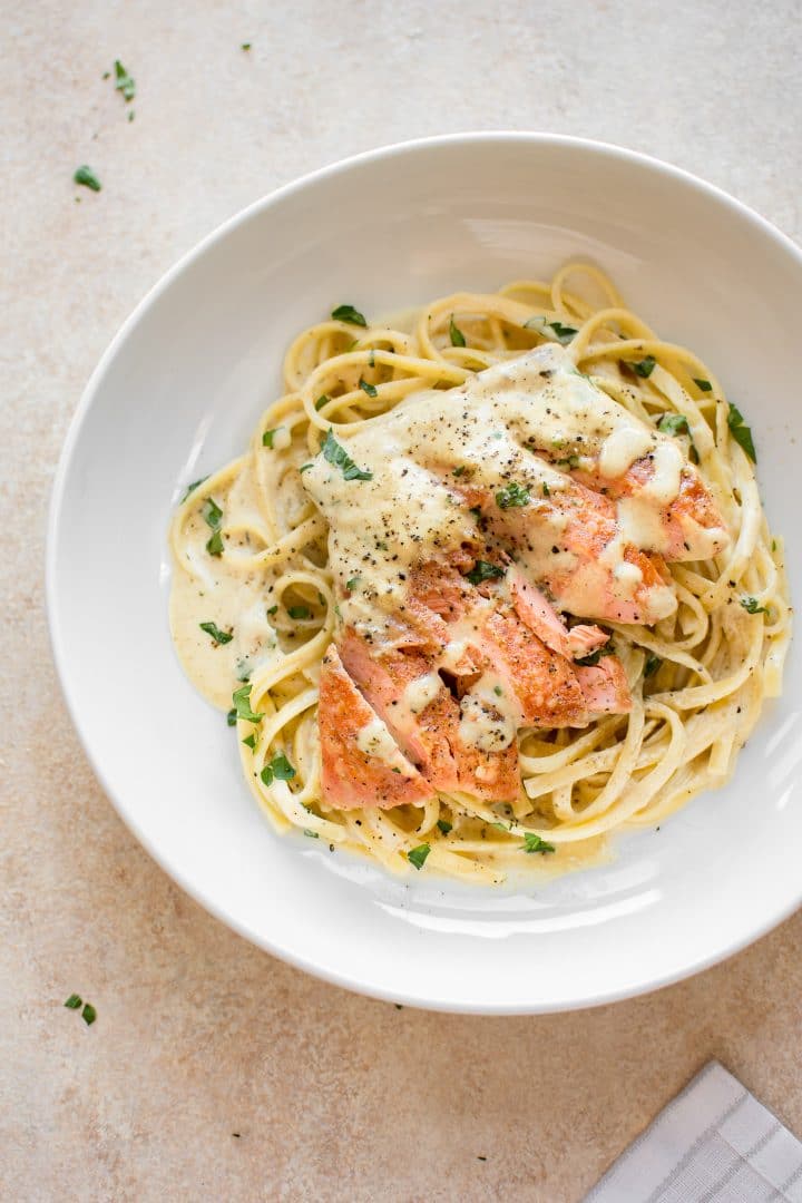 creamy dijon salmon over pasta on a ceramic white plate