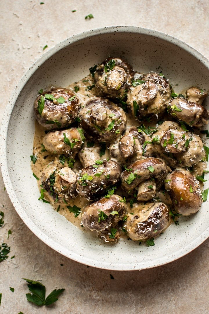 close-up of mushrooms with a creamy garlic sauce in a beige bowl