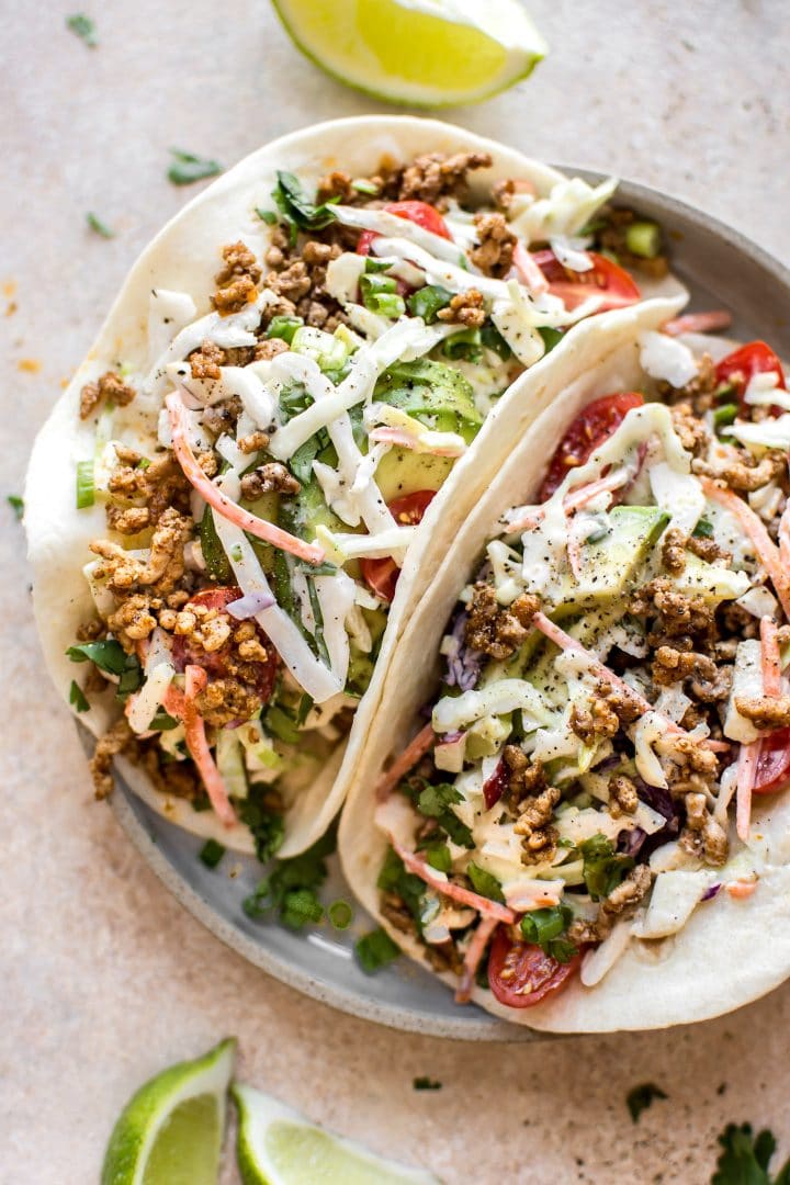 two ground pork tacos with homemade apple slaw on a plate