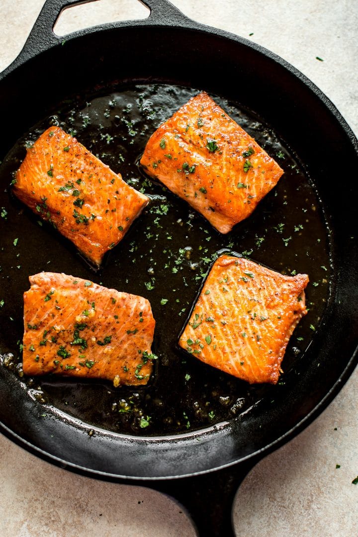 four pieces of pan-fried glazed honey garlic salmon in a cast iron skillet