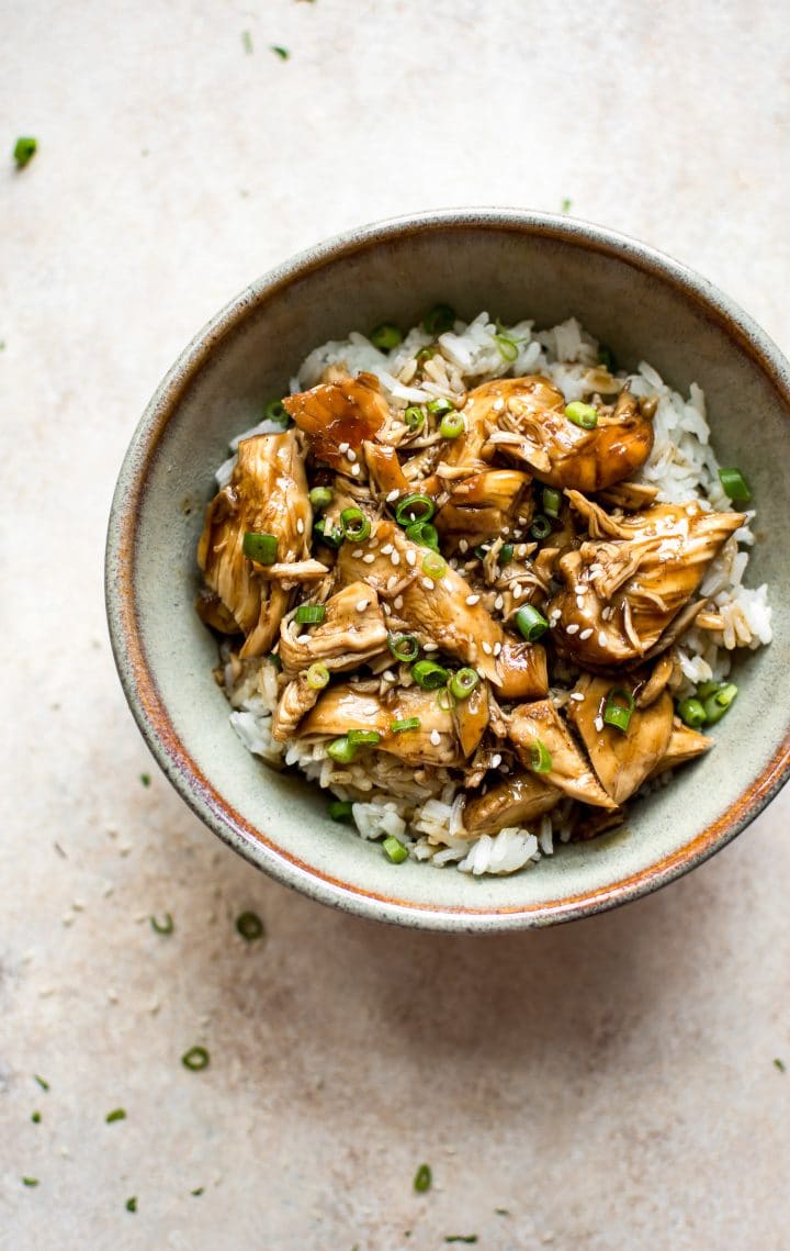 electric pressure cooker teriyaki chicken in a bowl over rice with chopped onions