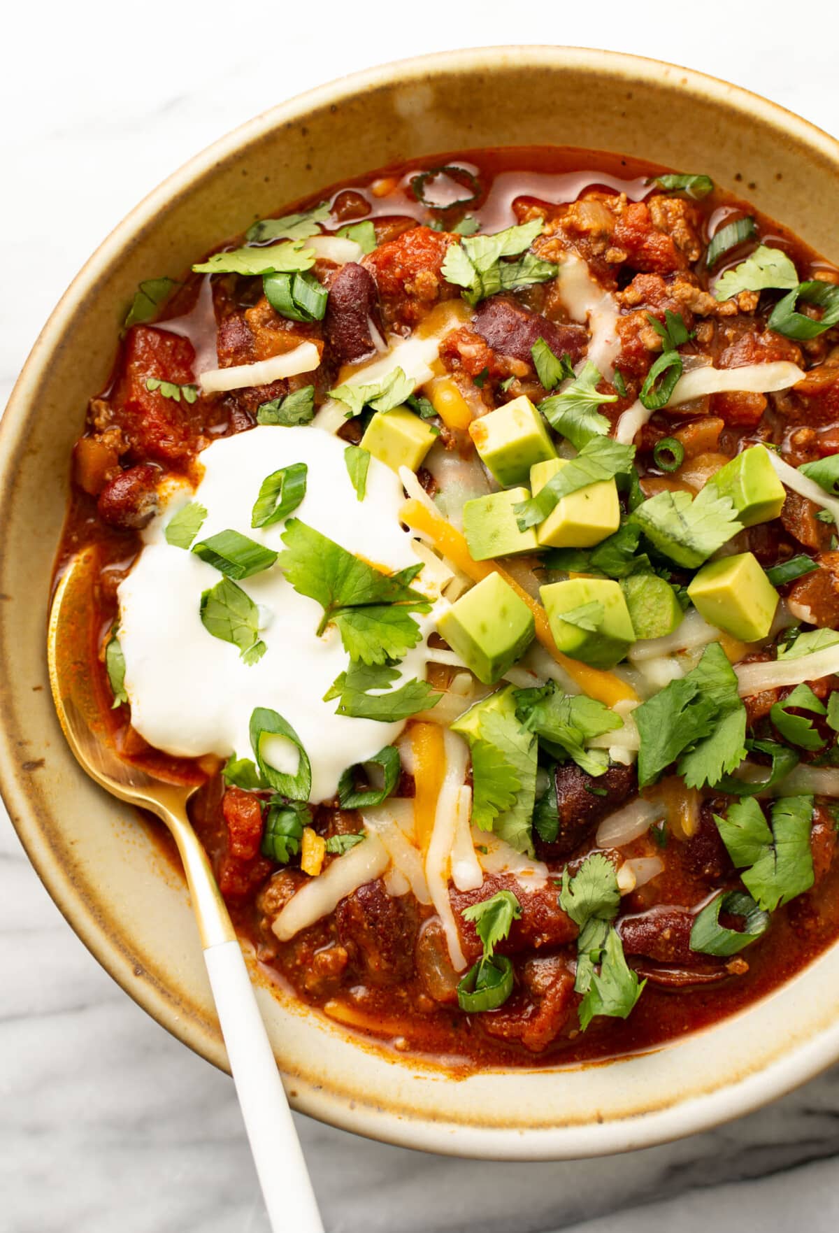 a bowl of quick chili with toppings and a spoon