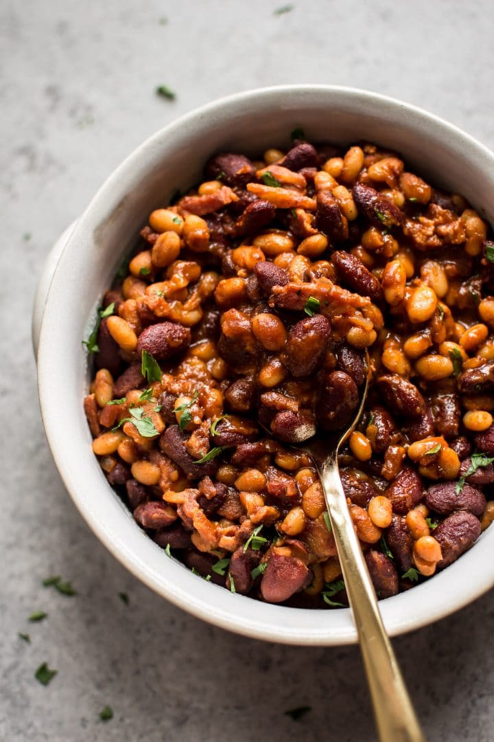 easy homemade baked beans with bacon in a white bowl with a spoon