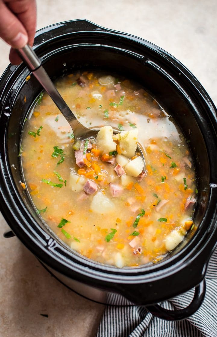 ham and potato soup inside a slow cooker with a ladle