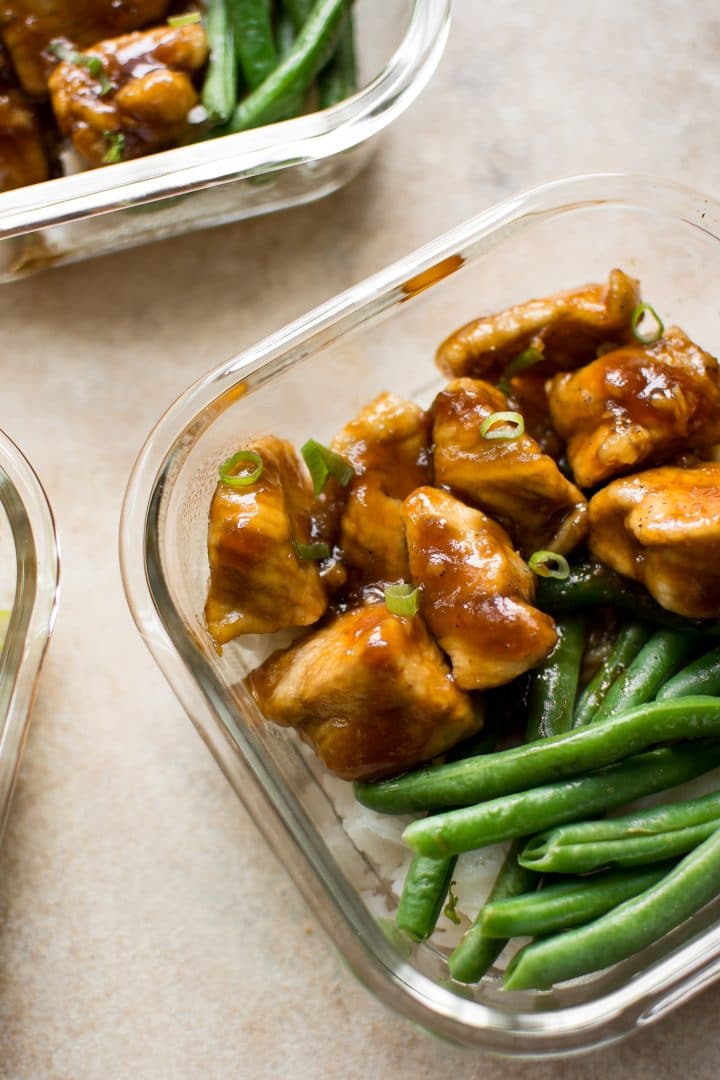 close-up of homemade mongolian chicken with rice and green beans in a glass container