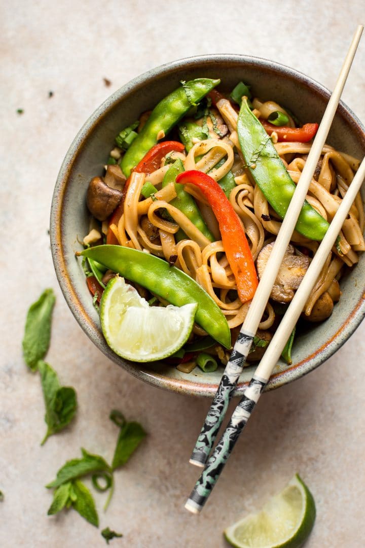 vegan rice noodles with sriracha hoisin ginger garlic sauce in a bowl with chopsticks resting on top