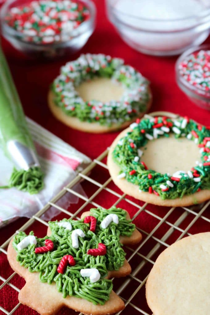 wreath and Christmas tree shaped sugar cookies with buttercream icing on a wire rack