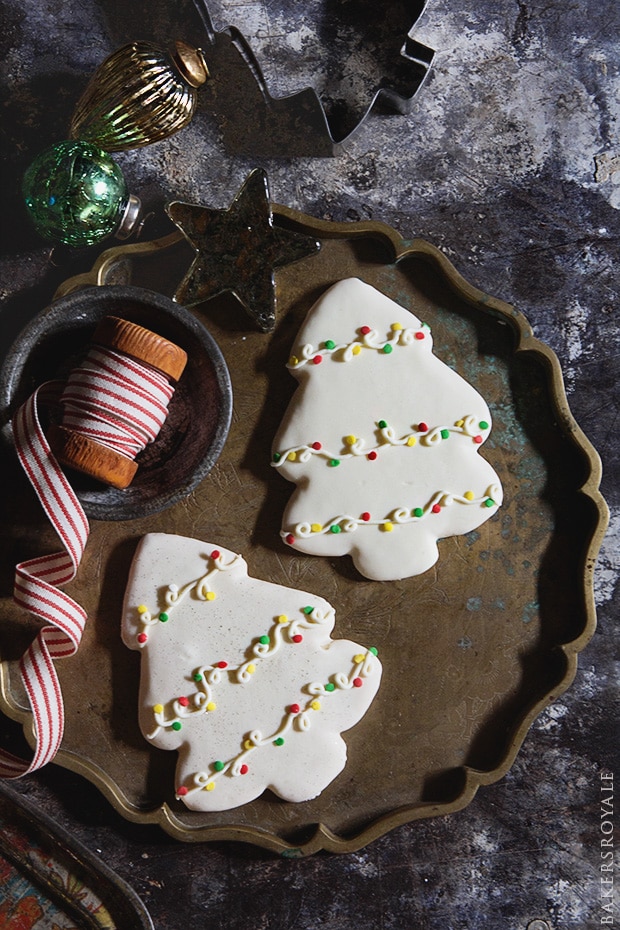 two christmas tree shaped cookies with delicately decorated icing on a plate