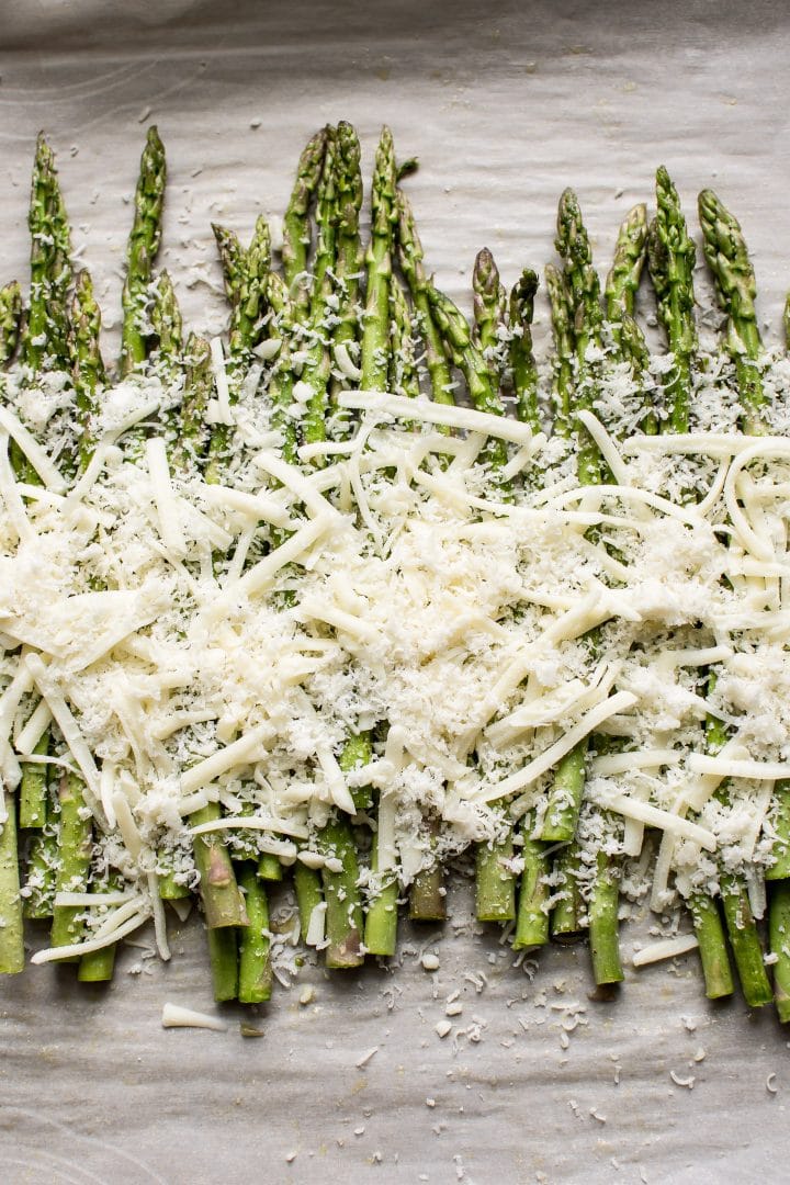process photo of asparagus covered with parmesan and mozzarella ready for the oven