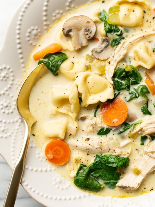 a bowl of creamy spinach chicken tortellini soup with a spoon