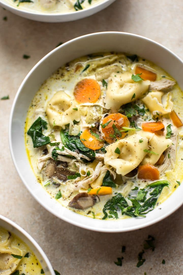close-up of spinach tortellini soup with chicken and carrots in a bowl
