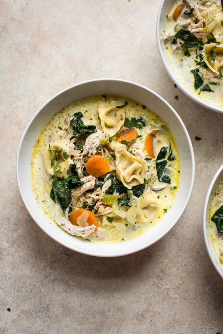 white bowl with chicken spinach tortellini soup with chicken and plenty of veggies
