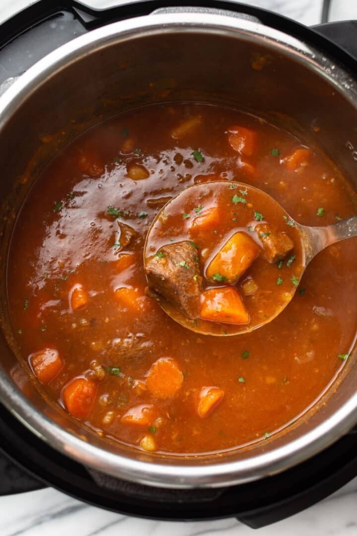 an instant pot with beef stew and a ladle