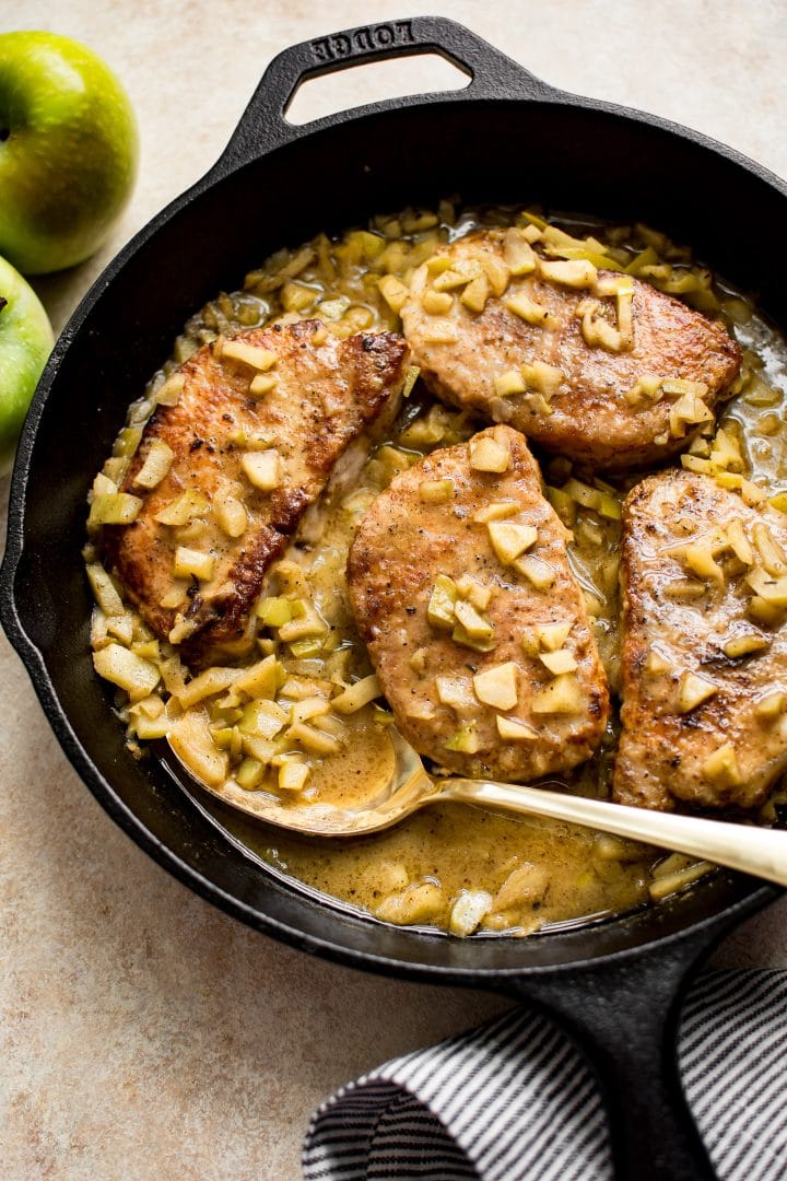 cast iron skillet with easy pork chops with chopped apples and a serving spoon