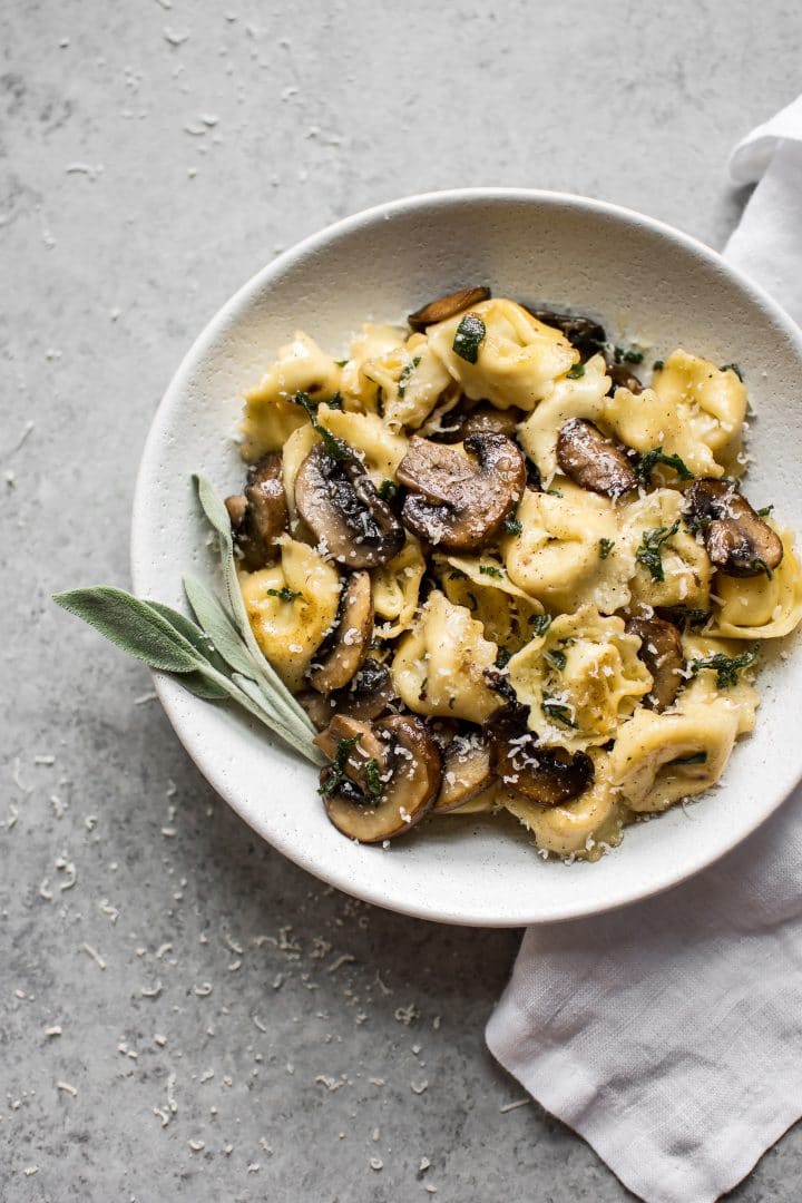 sage butter pasta recipe with mushrooms, parmesan cheese, and crispy sage in a white bowl