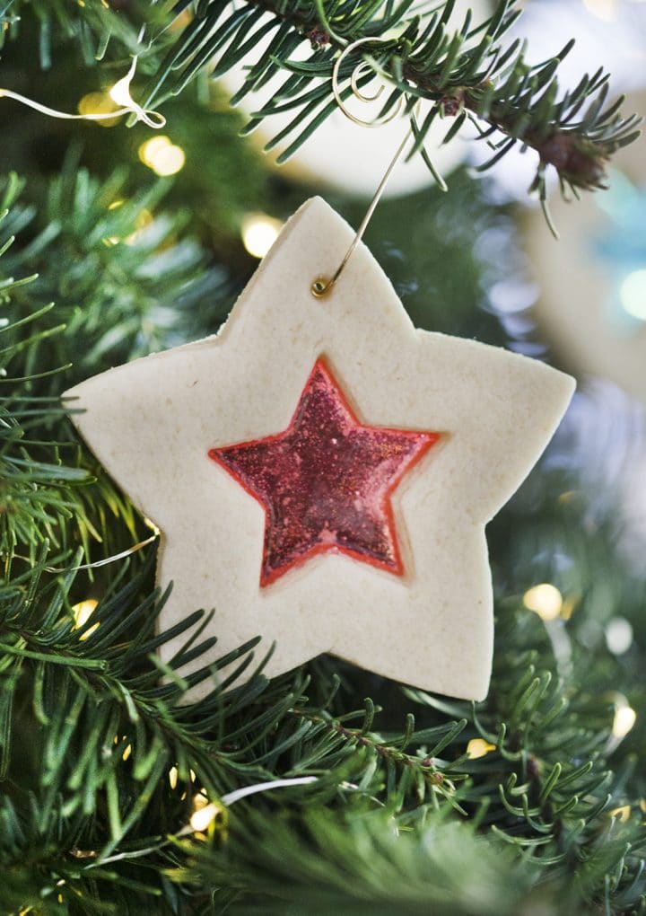 close-up of a star-shaped stained glass sugar cookie on a pine tree