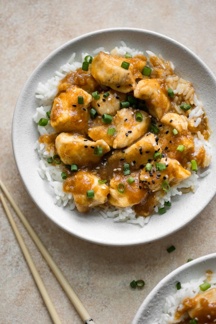 easy homemade mongolian chicken over rice in a white bowl beside chopsticks