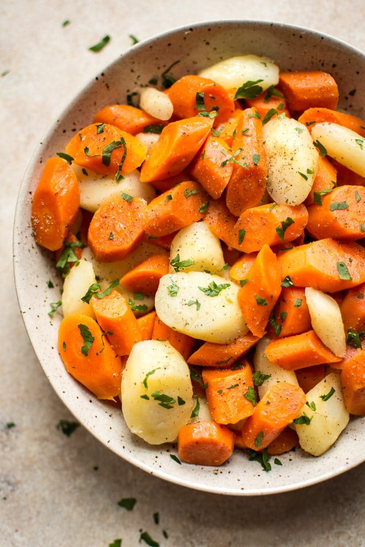 Instant Pot carrots and parsnips in a beige bowl topped with chopped parsley