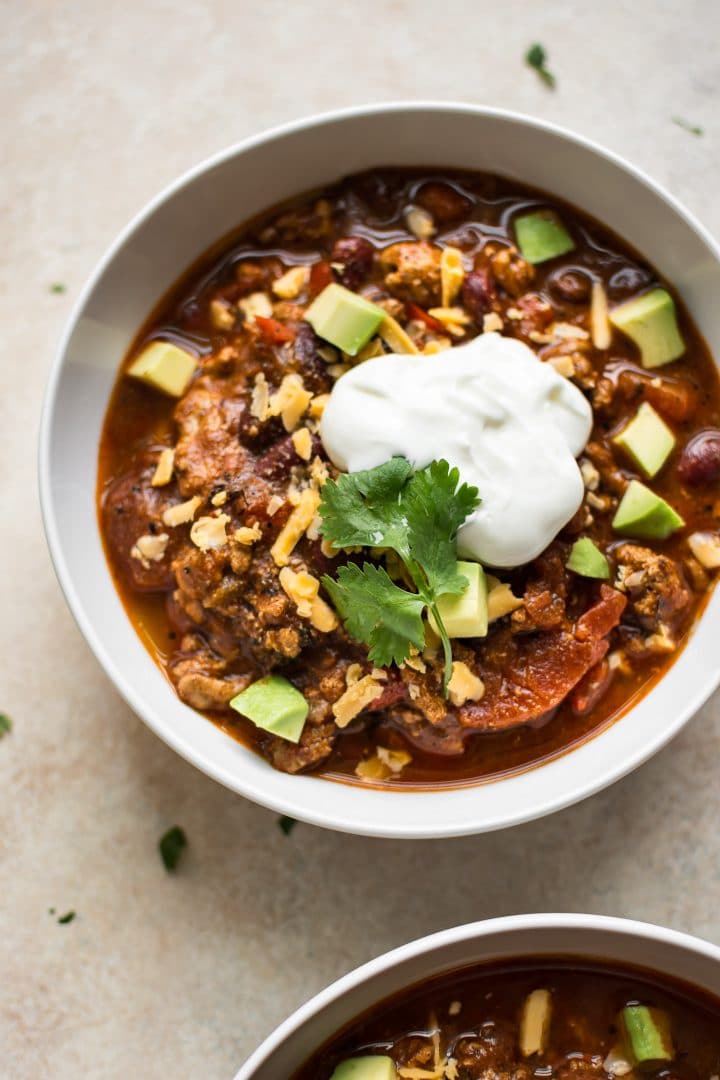 white bowl with Instant Pot turkey chili with beans topped with sour cream
