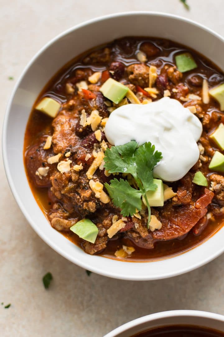 close-up of Instant Pot turkey chili in a white bowl topped with sour cream