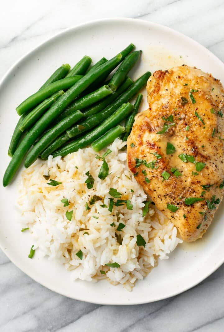 a plate with lemon chicken, green beans, and rice