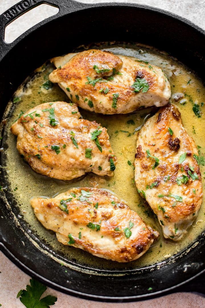 close-up of chicken breasts with a lemon butter sauce in a cast iron skillet