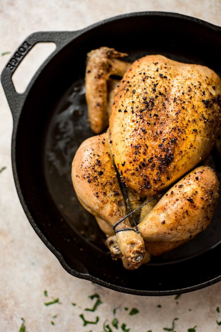 small seasoned roasted chicken with crispy skin in a cast iron pan