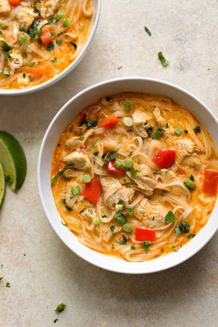 two white bowls of creamy Thai turkey soup next to lime slices