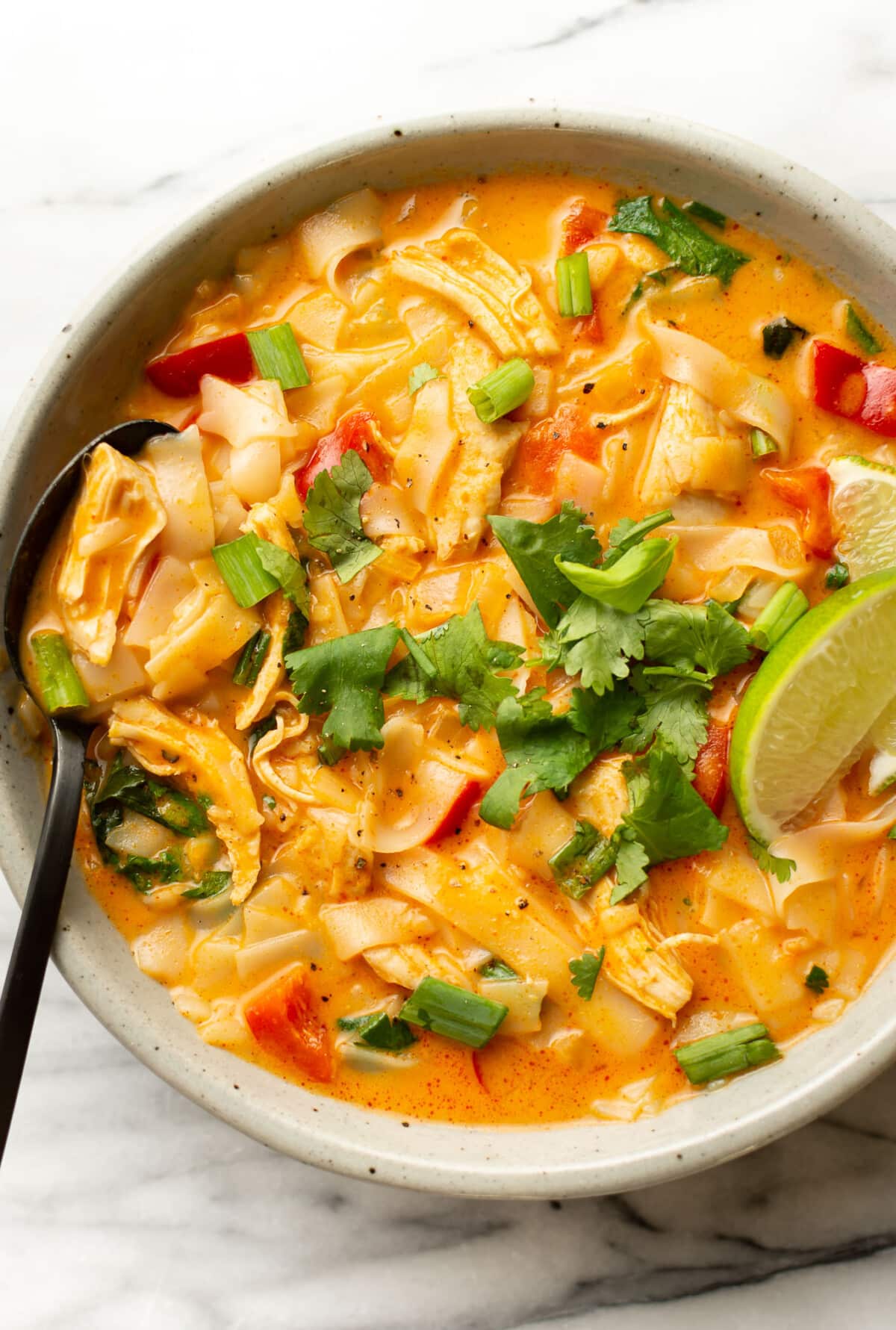 a bowl of thai turkey soup with a lime wedge and a spoon