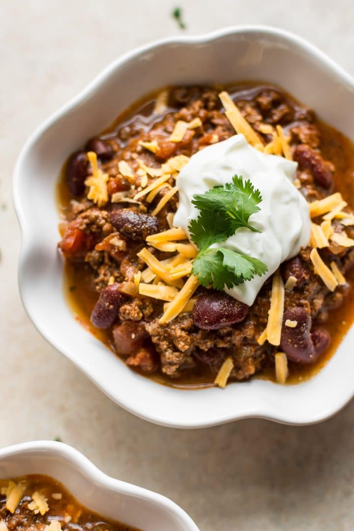 white bowl with quick and easy Instant Pot beef chili topped with sour cream and cheese
