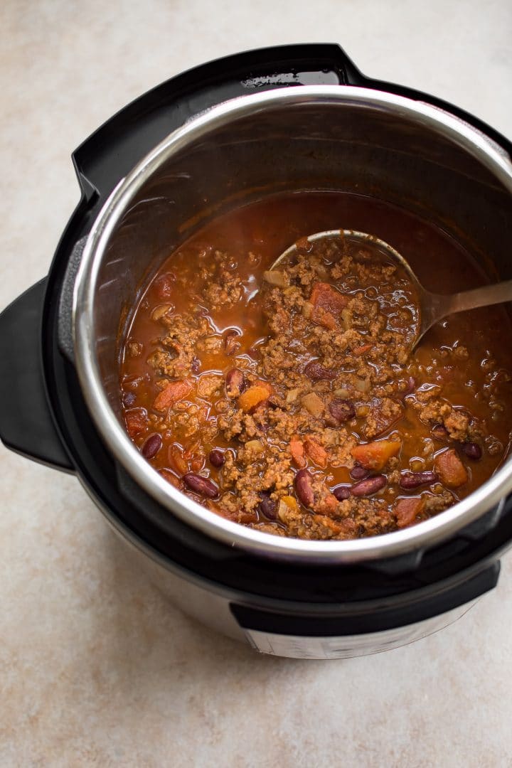 Instant Pot electric cooker with beef chili and a ladle