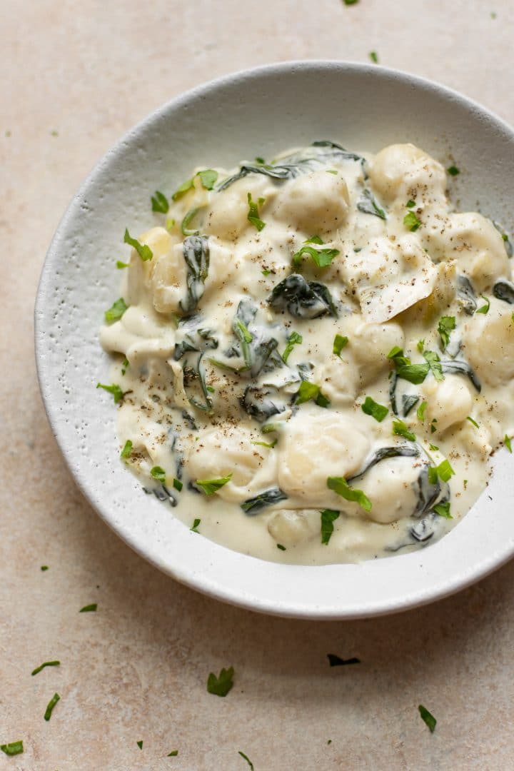 white bowl with spinach and artichoke creamy gnocchi