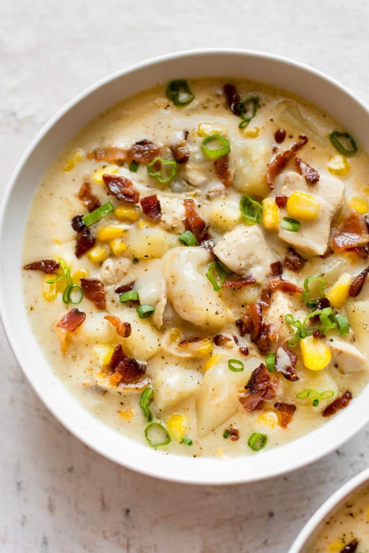 close-up of a white bowl with creamy chicken and corn chowder with bacon