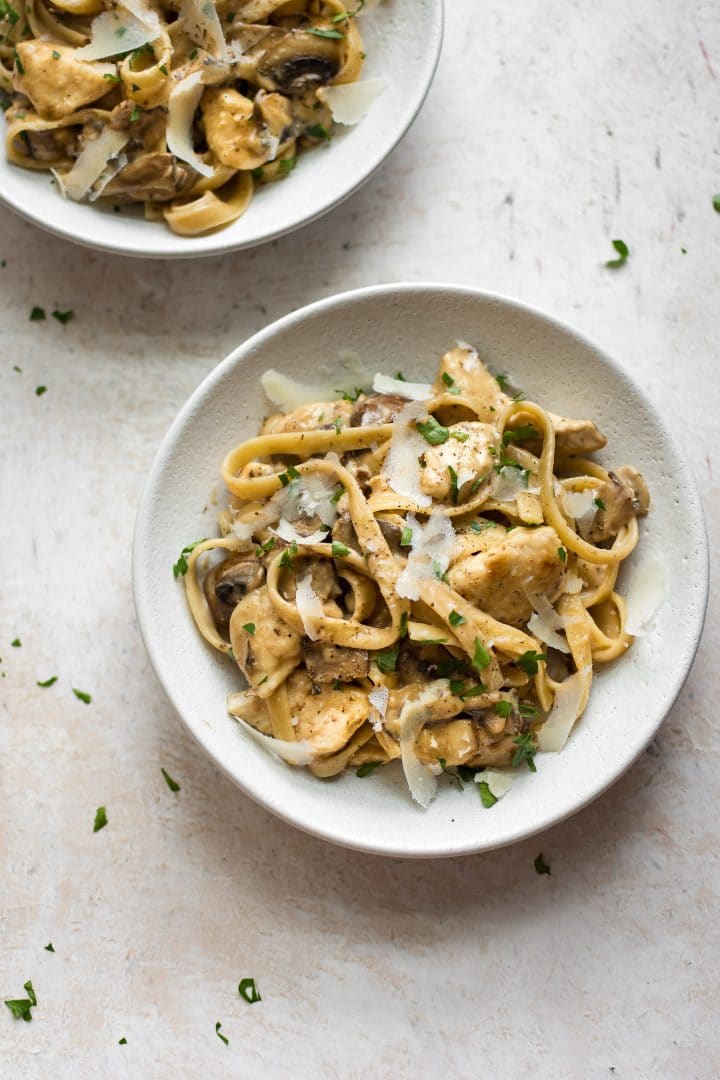 two bowls of creamy chicken marsala pasta with grated parmesan