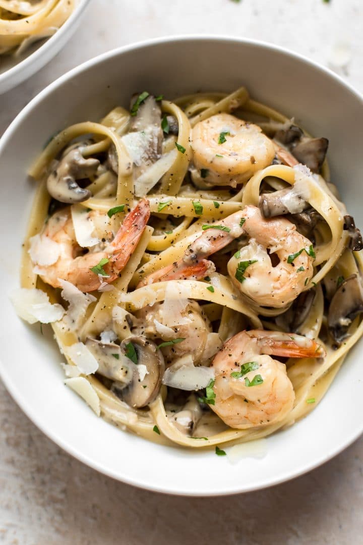 close-up of shrimp and mushroom pasta with a creamy alfredo sauce in a white bowl
